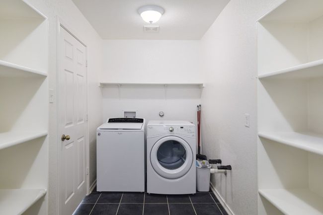 Washroom with washing machine and dryer, laundry area, visible vents, baseboards, and dark tile patterned floors | Image 17