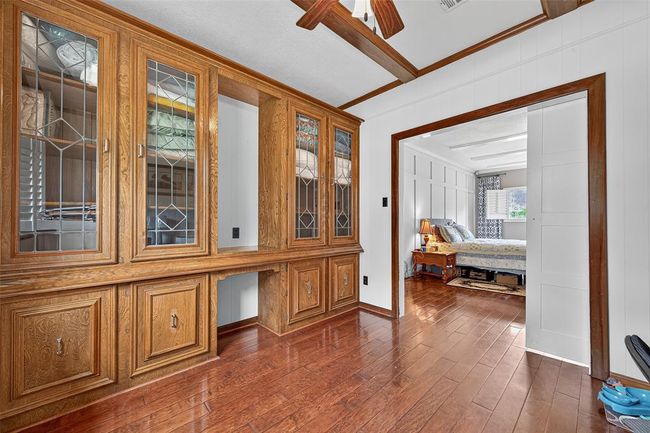 Just off the primary bedroom, this additional living space features full-wall built-ins and exposed wood ceiling beams—adding character and usefulness in one sweeping stroke. | Image 36