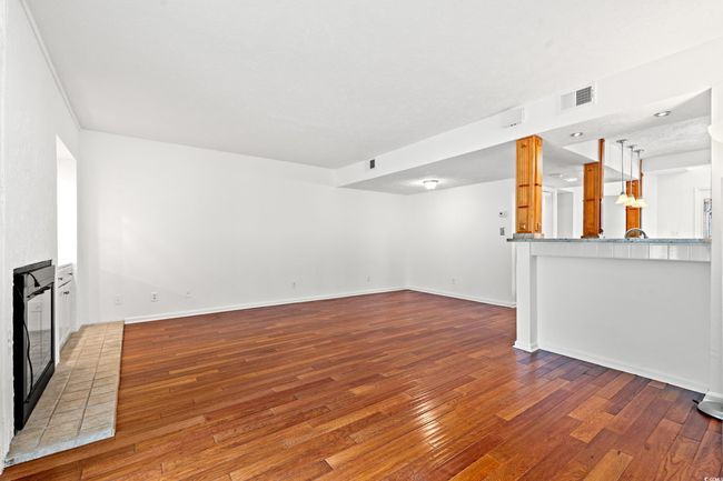 Unfurnished living room featuring wood-type flooring and a brick fireplace | Image 7
