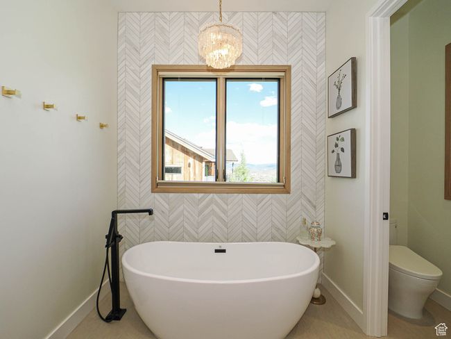 Full bathroom with a freestanding tub, a chandelier, and wallpapered walls | Image 51