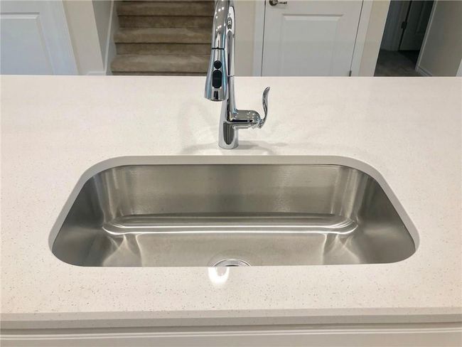 Kitchen view of a sink and light stone countertops | Image 6