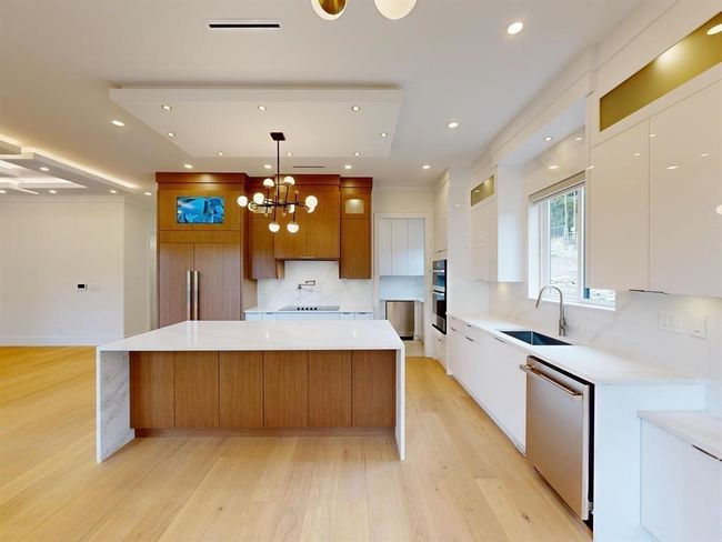 Kitchen featuring stainless steel appliances, modern cabinets, light wood-type flooring, a large island, and backsplash | Image 10