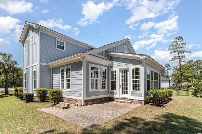 Rear view of property with board and batten siding, a lawn, a patio, and fence | Image 7