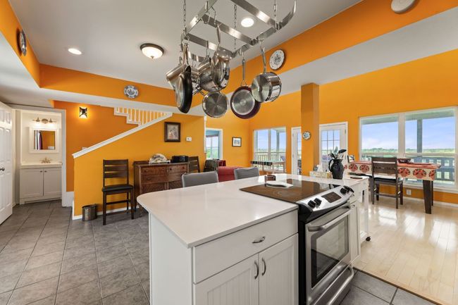 Kitchen with open floor plan, light countertops, a center island, electric range, and white cabinets | Image 11