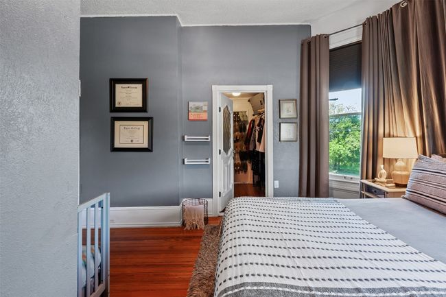 Bedroom featuring wood finished floors, a textured wall, and a walk in closet | Image 25