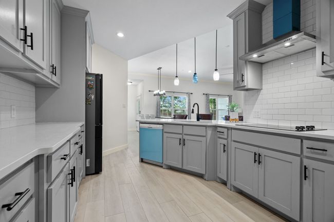 Kitchen featuring dishwashing machine, wall chimney range hood, gray cabinets, light countertops, and recessed lighting | Image 18