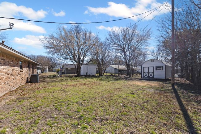 View of yard featuring central AC, fence, an outdoor structure, and a storage unit | Image 8