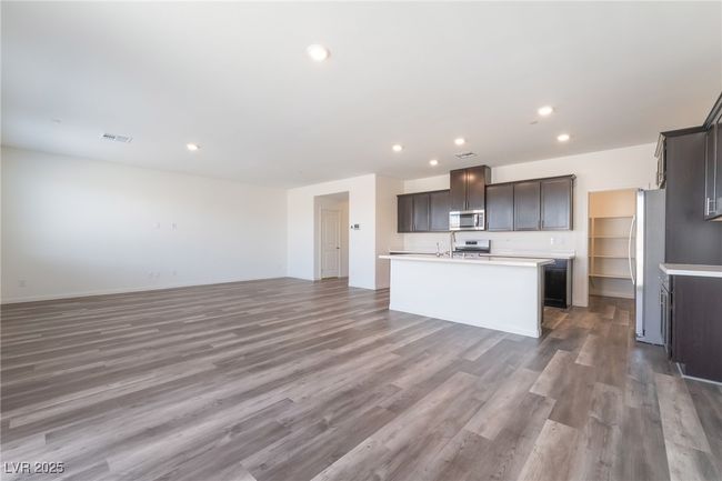 Kitchen with stainless steel microwave, open floor plan, a kitchen island with sink, recessed lighting, and wood finished floors | Image 9