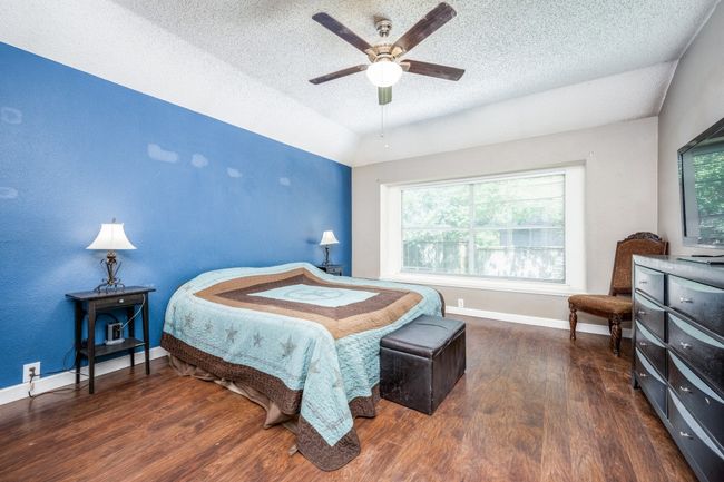 Bedroom with a textured ceiling, wood finished floors, a ceiling fan, and lofted ceiling | Image 14