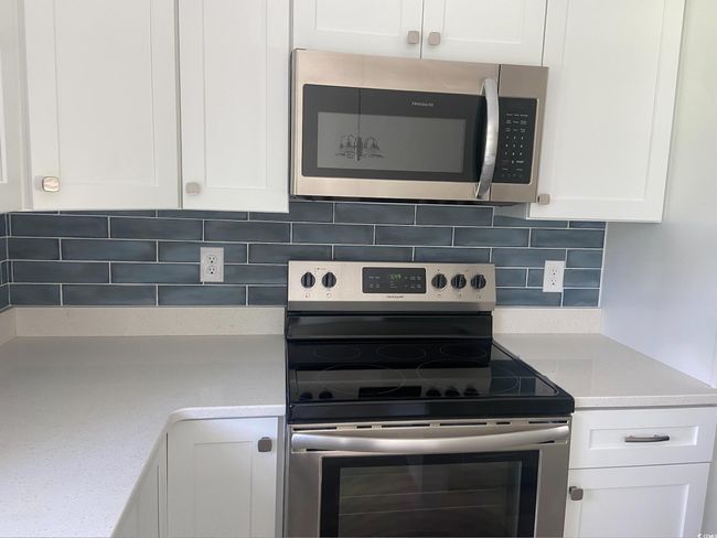 Kitchen featuring stainless steel appliances, white cabinetry, and tasteful backsplash | Image 14