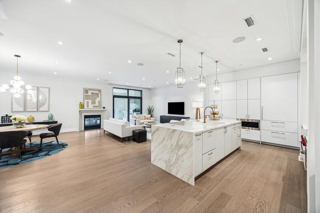 [Kitchen/Living Area] Breathtaking open concept floor plan showcasing crisp white lines, gleaming metallics and a focal point waterfall island | Image 8