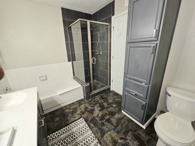 Bathroom with a bath, a shower stall, vanity, and toilet | Image 10