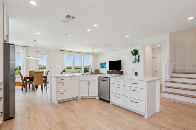 Kitchen with appliances with stainless steel finishes, a sink, light wood-style flooring, light countertops, and white cabinetry | Image 17