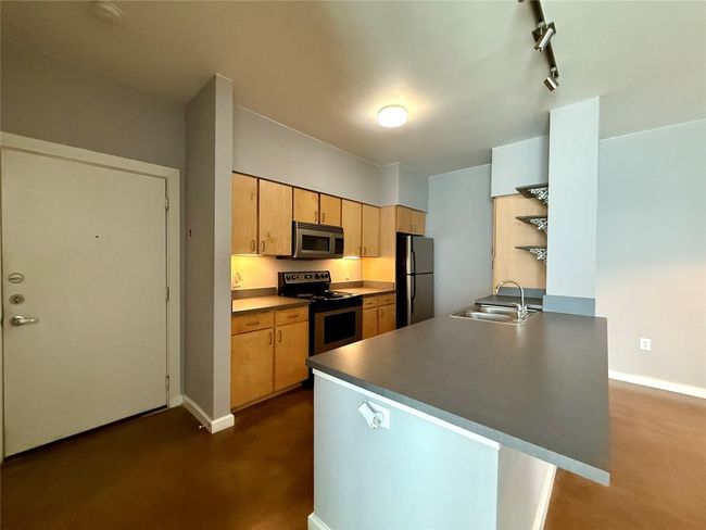 Kitchen featuring stainless steel appliances, a sink, baseboards, a peninsula, and rail lighting | Image 4