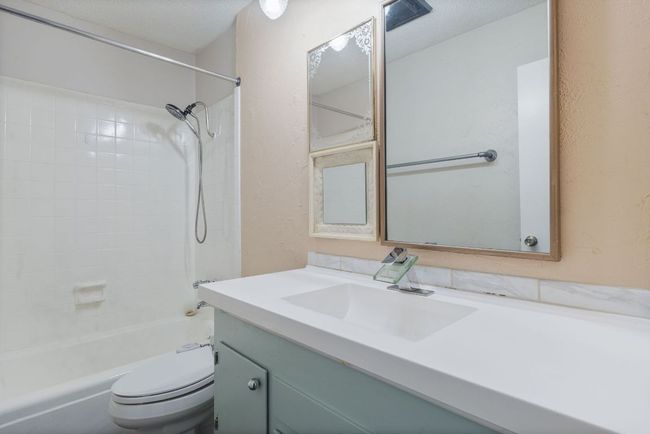 Full bath with vanity, bathing tub / shower combination, and a textured wall | Image 11