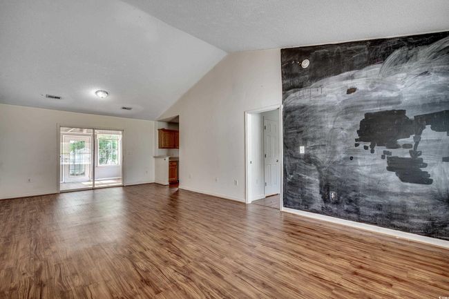 Unfurnished living room featuring wood finished floors and lofted ceiling | Image 18