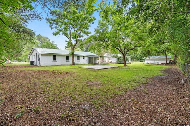 Rear view of property with a patio, metal roof, central AC unit, and concrete block siding | Image 13