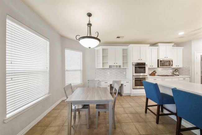 Bright & cheery, the breakfast room sits near the kitchen with pendant chandelier lighting, windows with blinds overlooking the backyard & tile floors. | Image 19