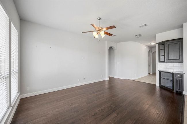 Unfurnished living room featuring visible vents, baseboards, ceiling fan, wood finished floors, and arched walkways | Image 22