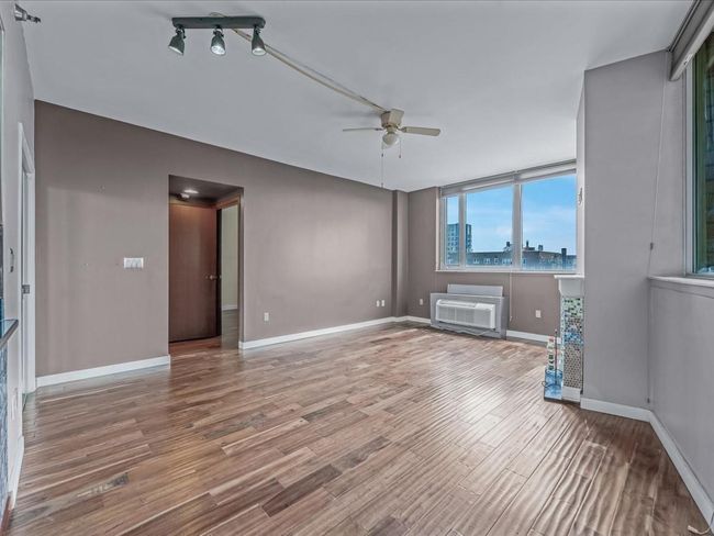 Spare room with a ceiling fan, wood finished floors, and an AC wall unit | Image 6