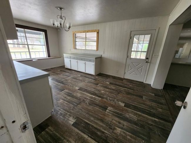 Unfurnished dining area with a chandelier, dark wood finished floors, and plenty of natural light | Image 10