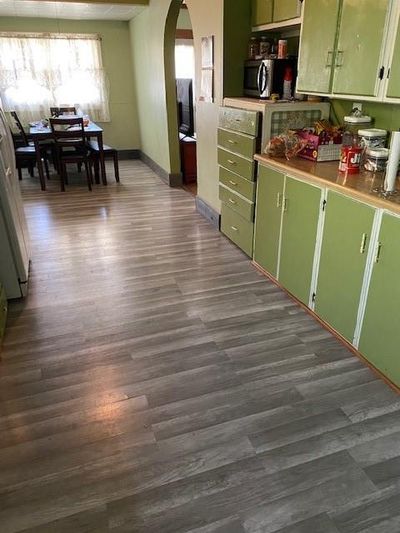 This large kitchen has newer flooring, painted cabinets, and goes directly into the dining room. Look at those cool archways to the living area! | Image 2