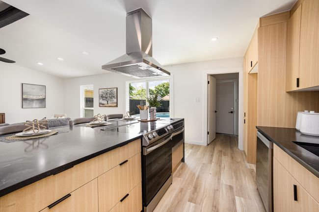 Kitchen with stainless steel range with electric cooktop, modern cabinets, island exhaust hood, open floor plan, and light brown cabinets | Image 19