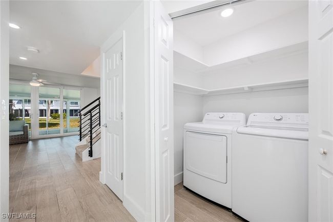 Laundry area in entry hallway, featuring shelving and separate washer and dryer. | Image 10