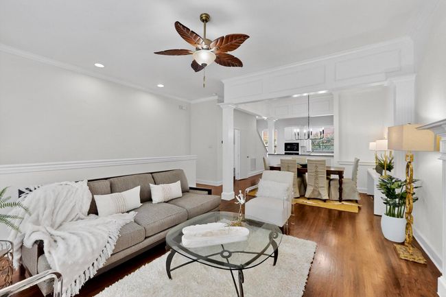 Living area with ornamental molding, dark wood-type flooring, a ceiling fan, decorative columns, and a chandelier | Image 13