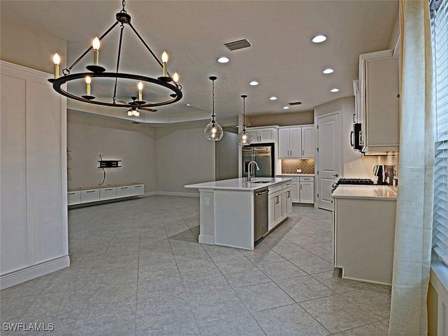 Kitchen with appliances with stainless steel finishes, a chandelier, light countertops, recessed lighting, and light tile patterned floors | Image 11