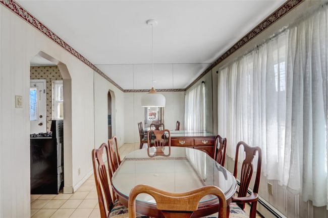 Dining room with light tile patterned floors, arched walkways, and baseboard heating | Image 8