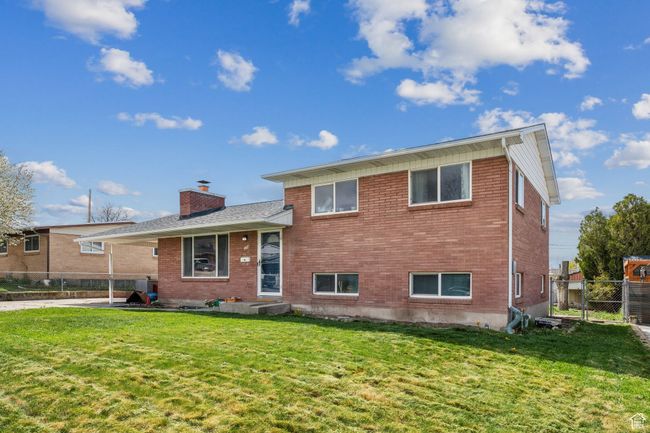 View of front facade featuring brick siding, a front lawn, fence, and a chimney | Image 27