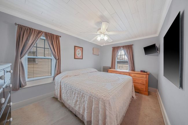Bedroom with wooden ceiling, ornamental molding, baseboards, ceiling fan, and light carpet | Image 15