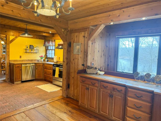 Kitchen with brown cabinetry, wood ceiling, stainless steel appliances, light countertops, and a sink | Image 12