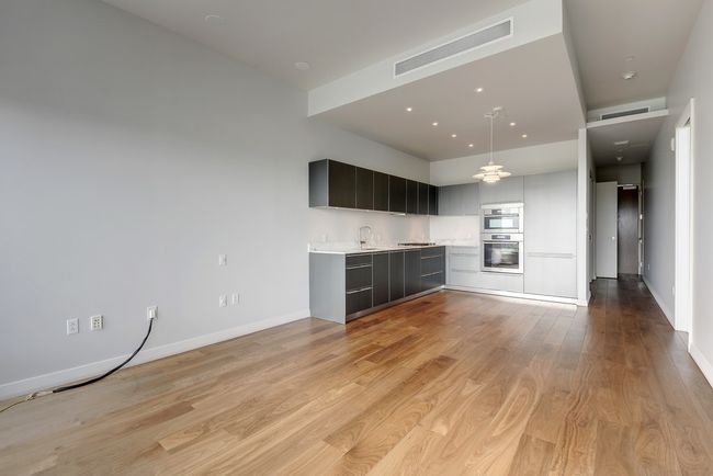 Kitchen featuring modern cabinets, light countertops, light wood-style flooring, baseboards, and recessed lighting | Image 6