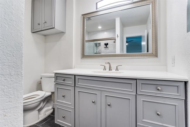 Bathroom with toilet, vanity, a shower, and a textured wall | Image 12