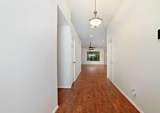 Upon opening the entry door, one is greeted by an expansive hallway adorned with warm flooring, evoking a serene and inviting ambiance that embodies the essence of home and its comforts. | Image 6