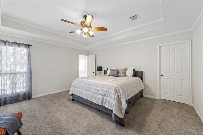 Bedroom with visible vents, carpet floors, a raised ceiling, and crown molding | Image 17