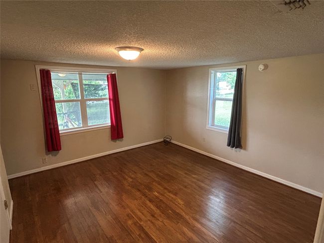 Spare room featuring a textured ceiling, dark wood finished floors, plenty of natural light, and a smoke detector | Image 22