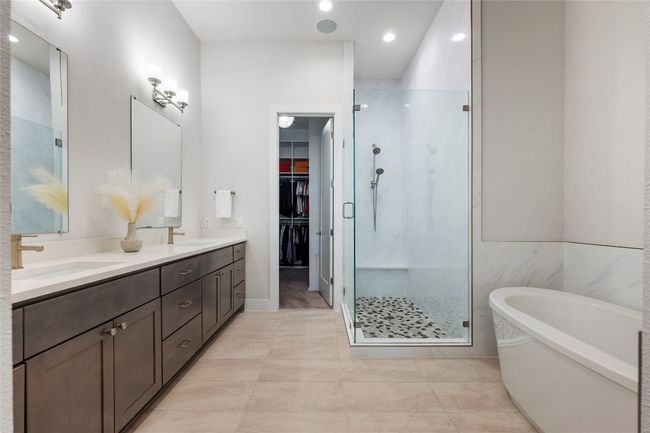 Elegant ensuite oversized primary bathroom features quartz countertops, dual vanity, soaking tub, walk-in shower and walk-in closet. | Image 12