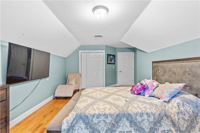 Bedroom with baseboards, wood finished floors, vaulted ceiling, and a closet | Image 24