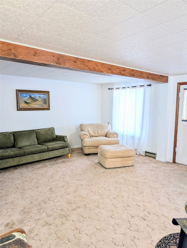 Unfurnished living room featuring a baseboard heating unit, carpet flooring, and beam ceiling | Image 19