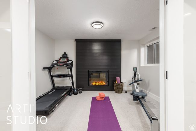 Exercise room with baseboards, a textured ceiling, visible vents, and a fireplace | Image 27