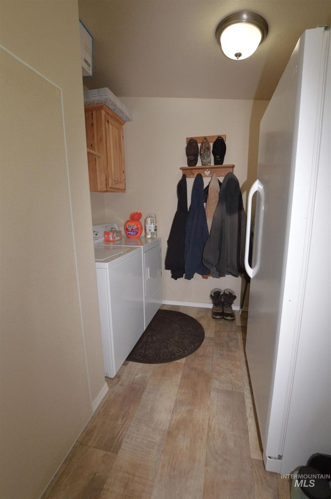 Laundry area featuring washing machine and dryer, cabinet space, and light wood finished floors | Image 11