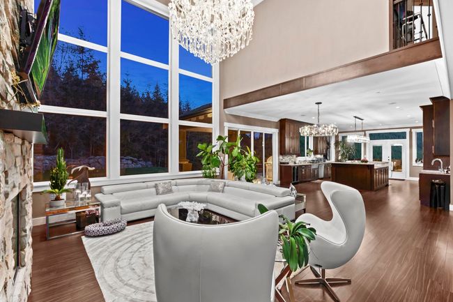 Living area with dark wood-style flooring, a towering ceiling, and a chandelier | Image 6