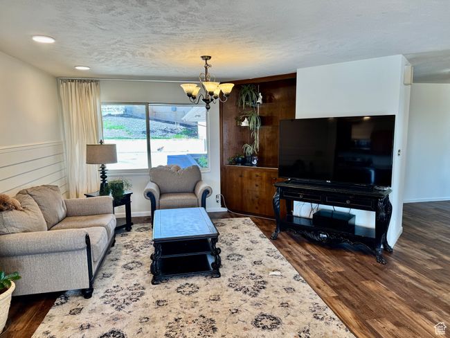 Living area with a chandelier, wood finished floors, and a textured ceiling | Image 6