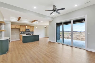 Kitchen featuring light wood-type flooring, backsplash, a center island, decorative light fixtures, and gas range | Image 3