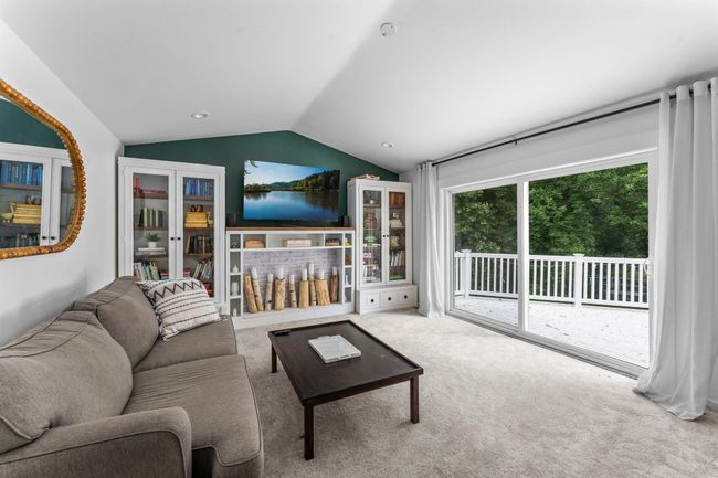 Just beyond, the large family room invites you to relax with vaulted ceilings, plush carpeting, and another set of sliding doors that lead to the deck. With such a thoughtful, flowing layout, the main living spaces are ideal for entertaining. | Image 10