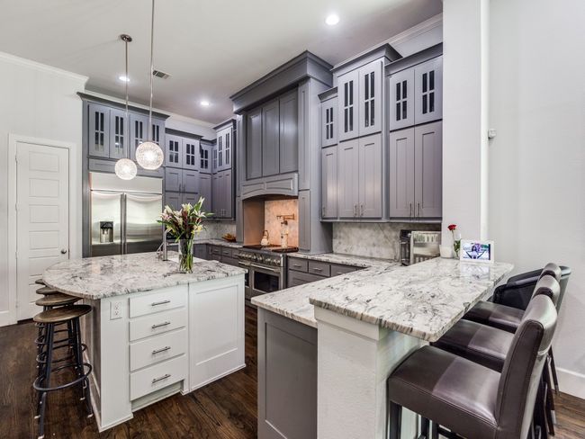 Kitchen featuring high quality appliances, crown molding, a breakfast bar, decorative backsplash, and a peninsula | Image 4