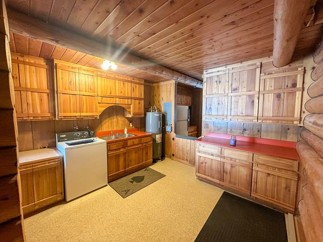 Clothes washing area with water heater, cabinets, washer / dryer, wooden ceiling, and wood walls | Image 20
